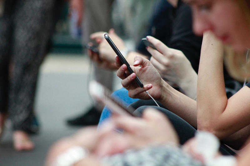 students looking at their mobile phones. Image by Robin Worrall on Unsplash. 