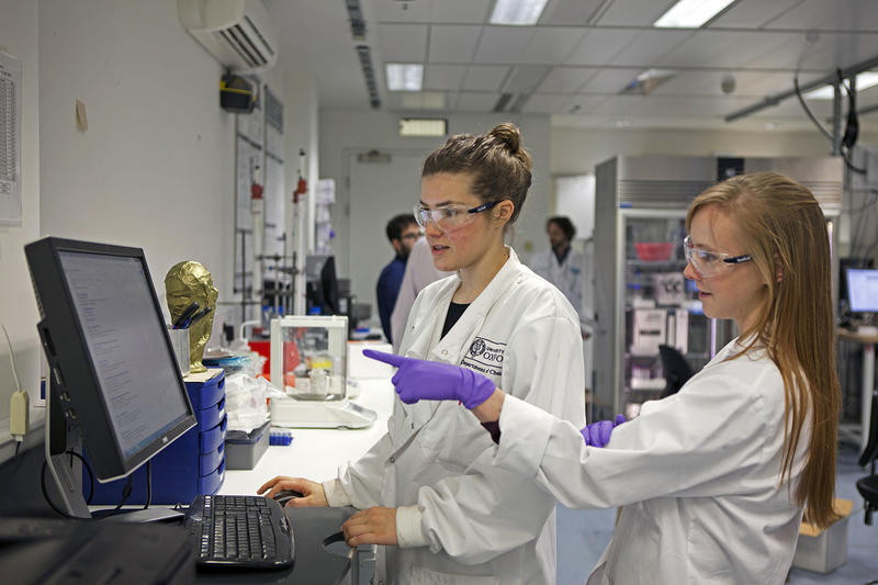 Two students looking and pointing at a computer screen inside a laboratory. Photo by Peter Hudston.