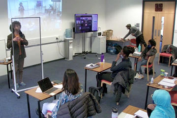 A hybrid of students being taught in-person in a classroom and online from a remote location
